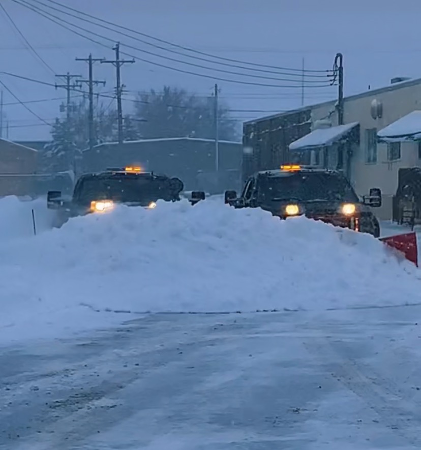 Two Sharp Image plow trucks pushing heavy snow during a storm